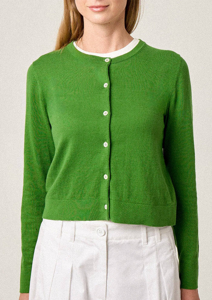 Green cardigan worn by a person on a plain background