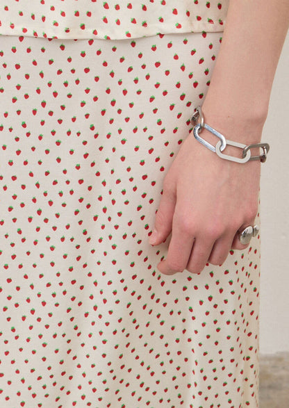 A person wearing an ivory slip skirt with small red strawberry print.