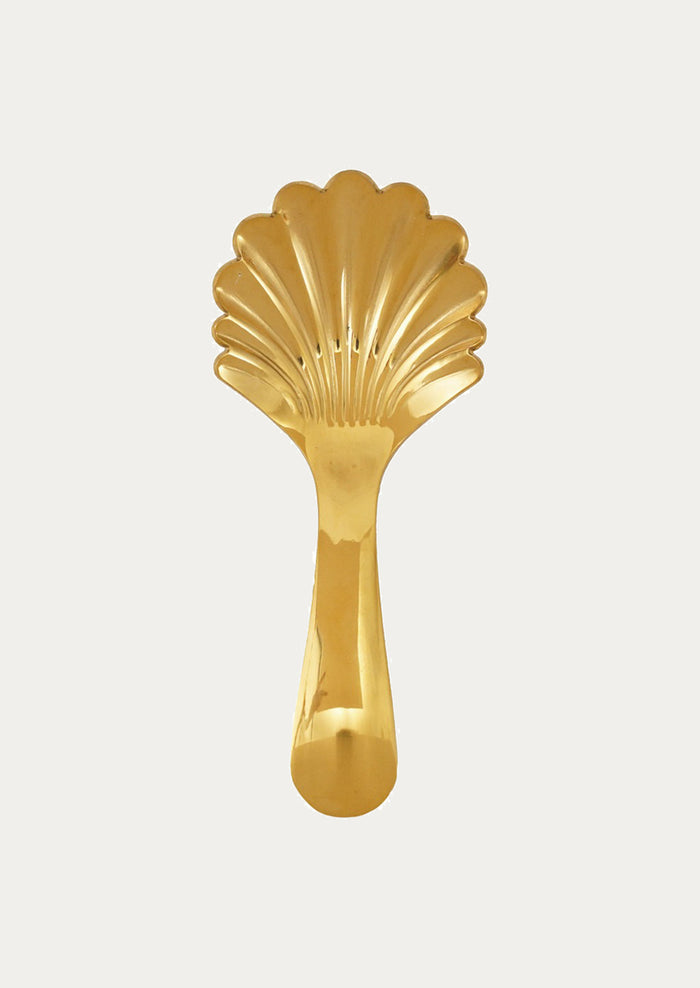 Gold shell-shaped spoon on a white background