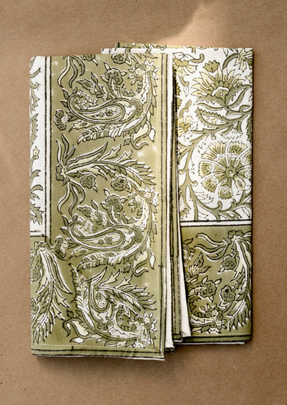 A set of cloth napkins in green and white traditional floral block print pattern.