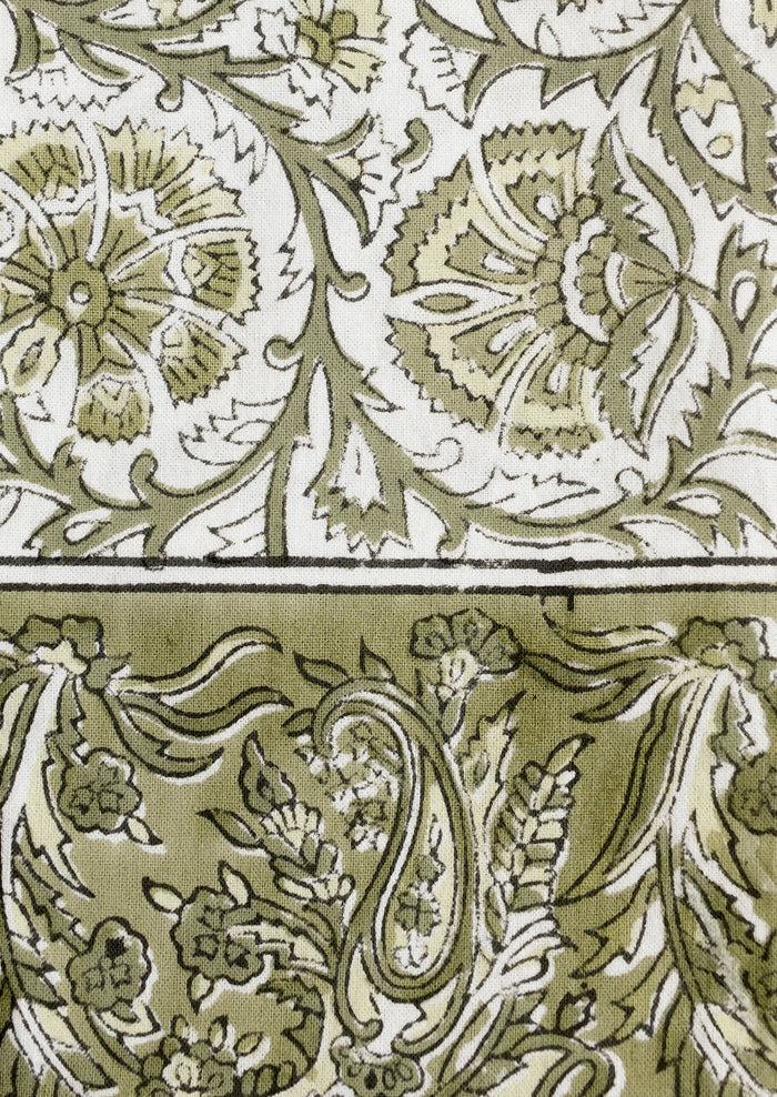 A set of cloth napkins in green and white traditional floral block print pattern.