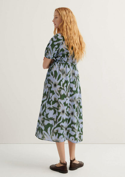 Woman wearing a patterned dress standing against a white background