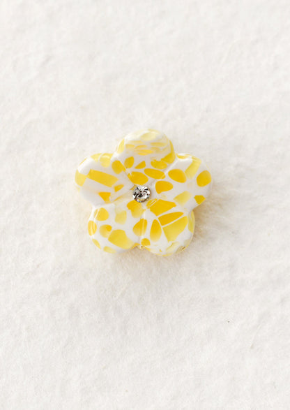 Yellow flower-shaped hair claw with a central gemstone on a white background