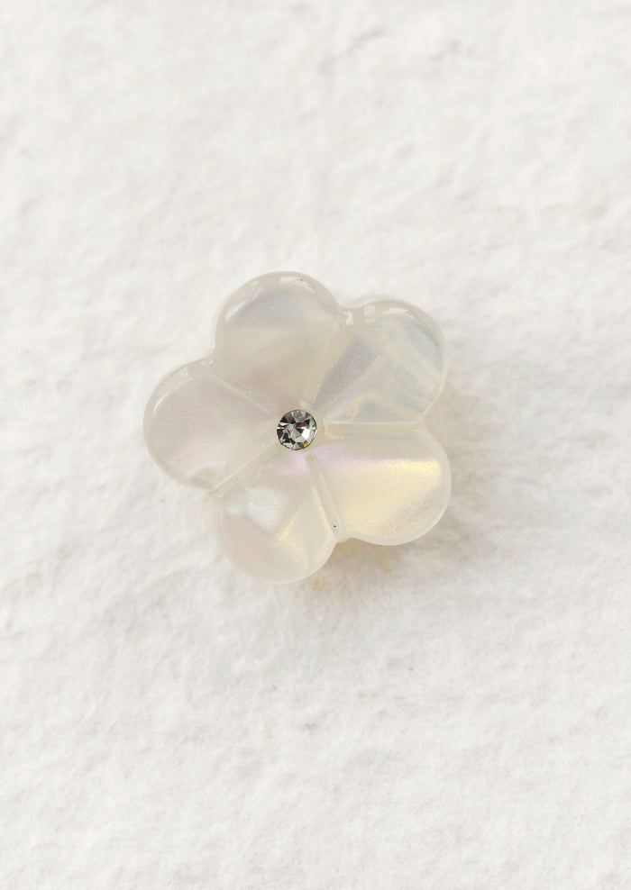 Pearl white flower-shaped mini hair claw on a textured white background