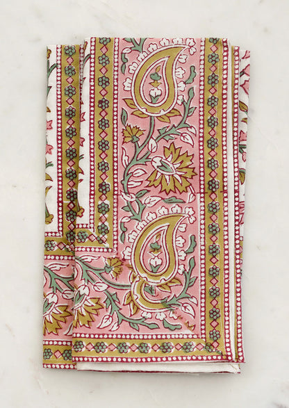 A set of cloth napkins in pink and mustard paisley print.