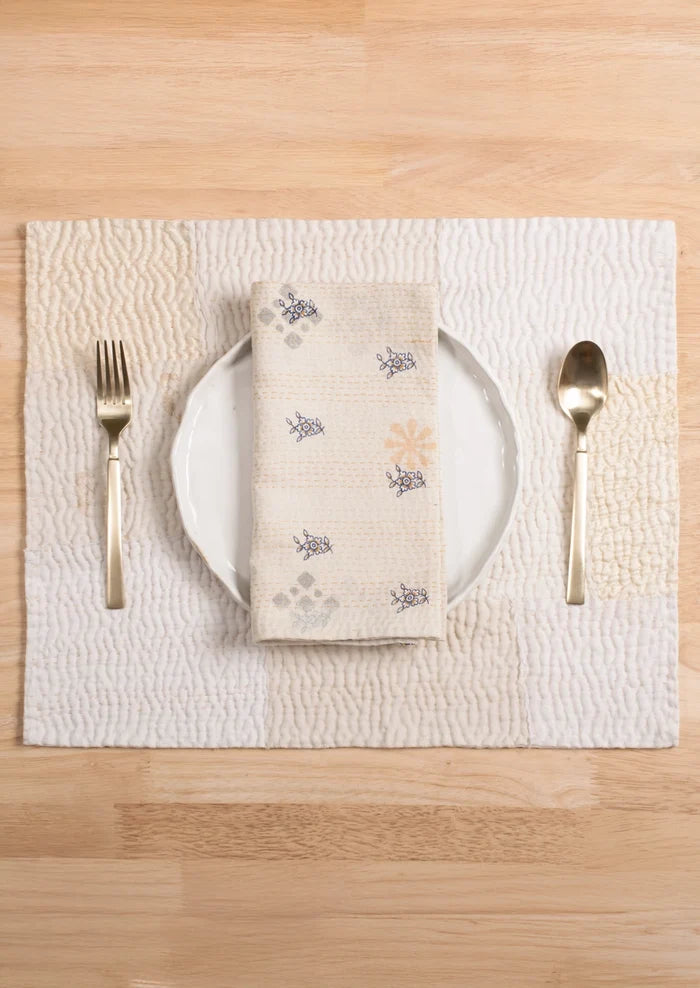 A patchwork placemat made from recycled vintage saris, in cream color palette.