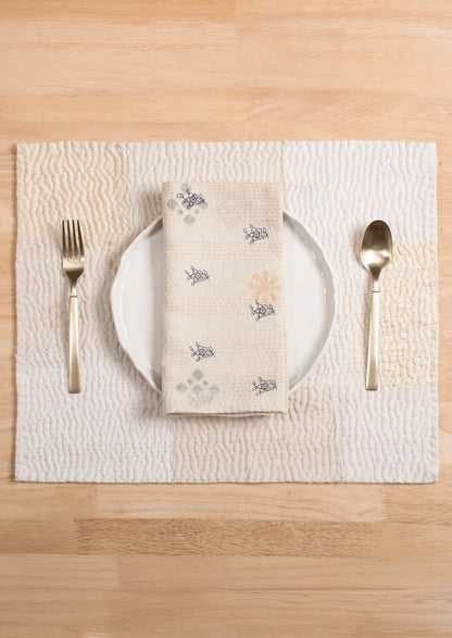 A patchwork placemat made from recycled vintage saris, in cream color palette.