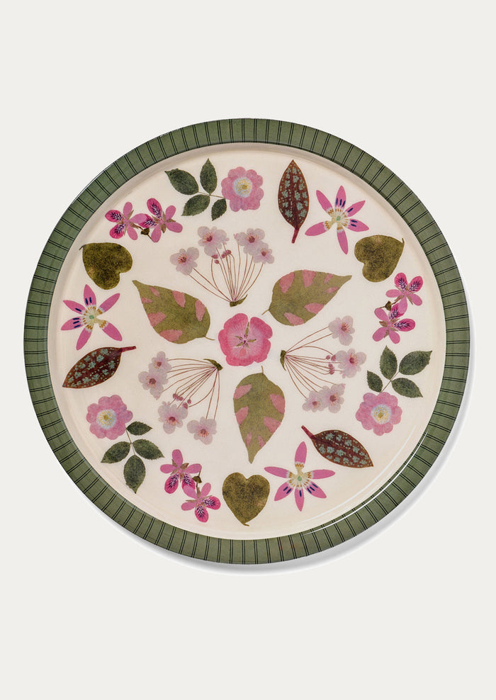 Round ceramic plate with floral and leaf pattern on a white background