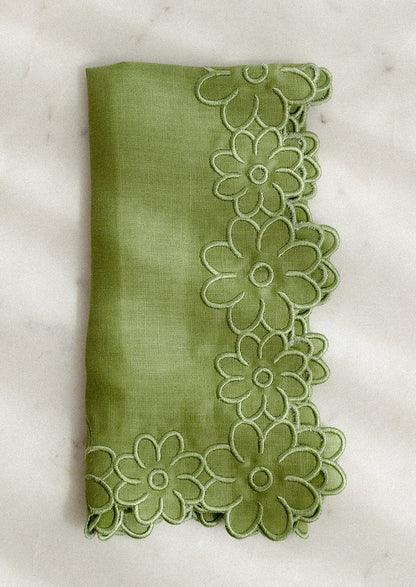 Green fabric napkin with floral trim on a white background