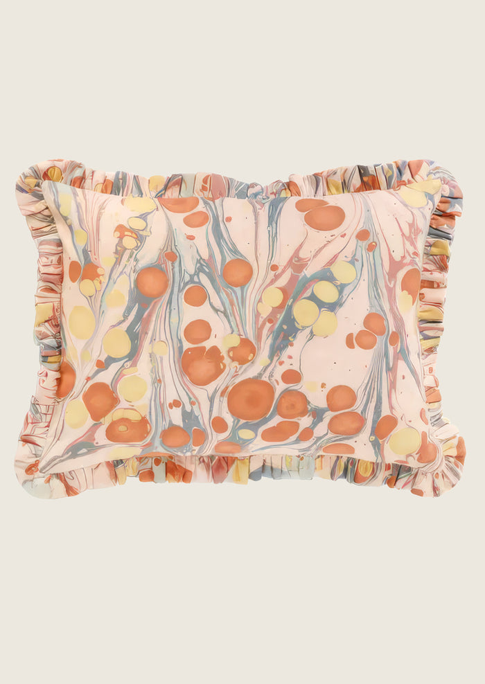 Decorative pillow with marbleized pattern and ruffled edges on a white background