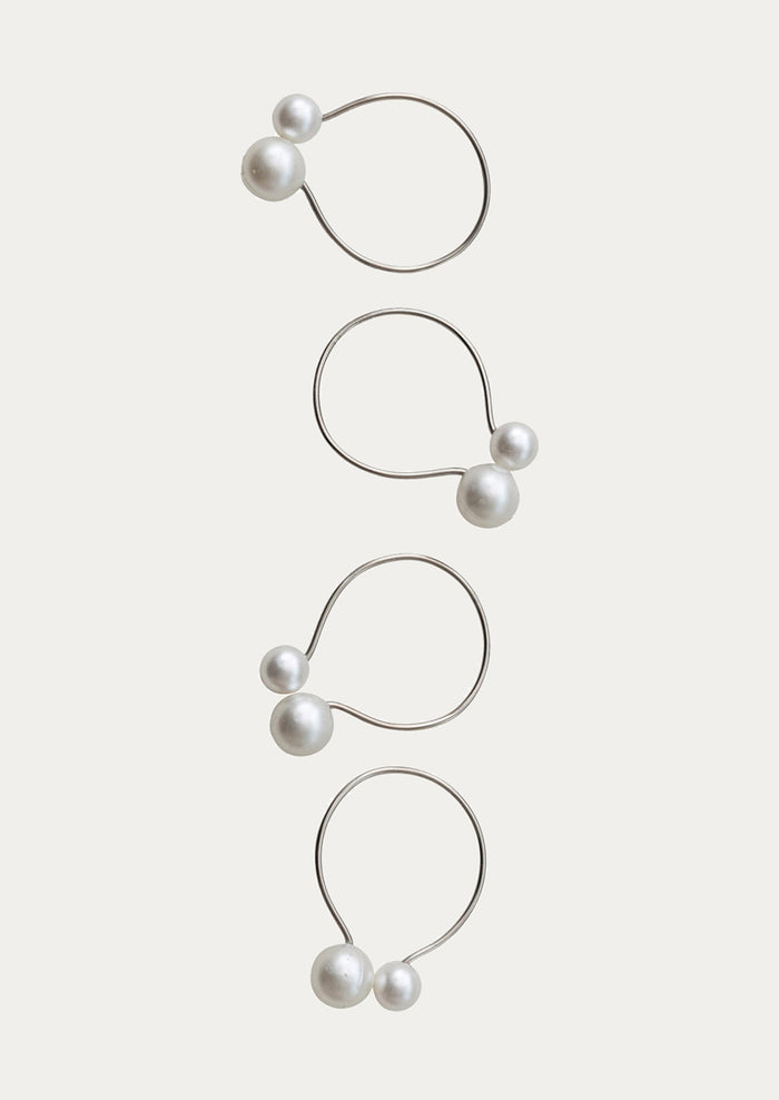 Set of four pearl earrings on a light beige background