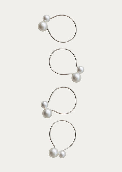 Set of four pearl earrings on a light beige background