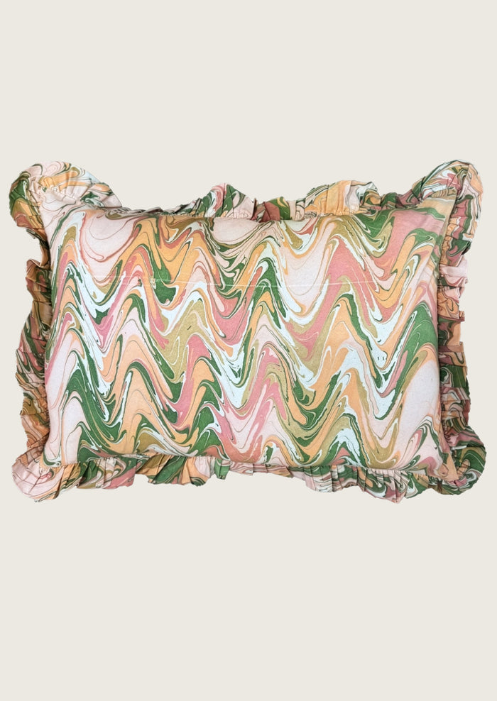 A rectangular ruffled pillow featuring a multicolor wavy marble pattern in shades of green, pink, orange, and cream, set against a solid light beige background.