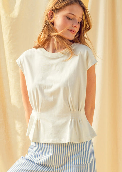 Woman wearing a white sleeveless top with a peplum waist against a beige background