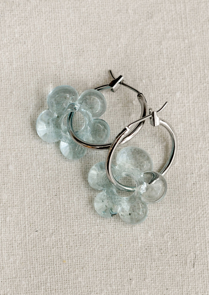 A pair of silver hoop earrings with floral Murano glass accents, displayed against a white background.