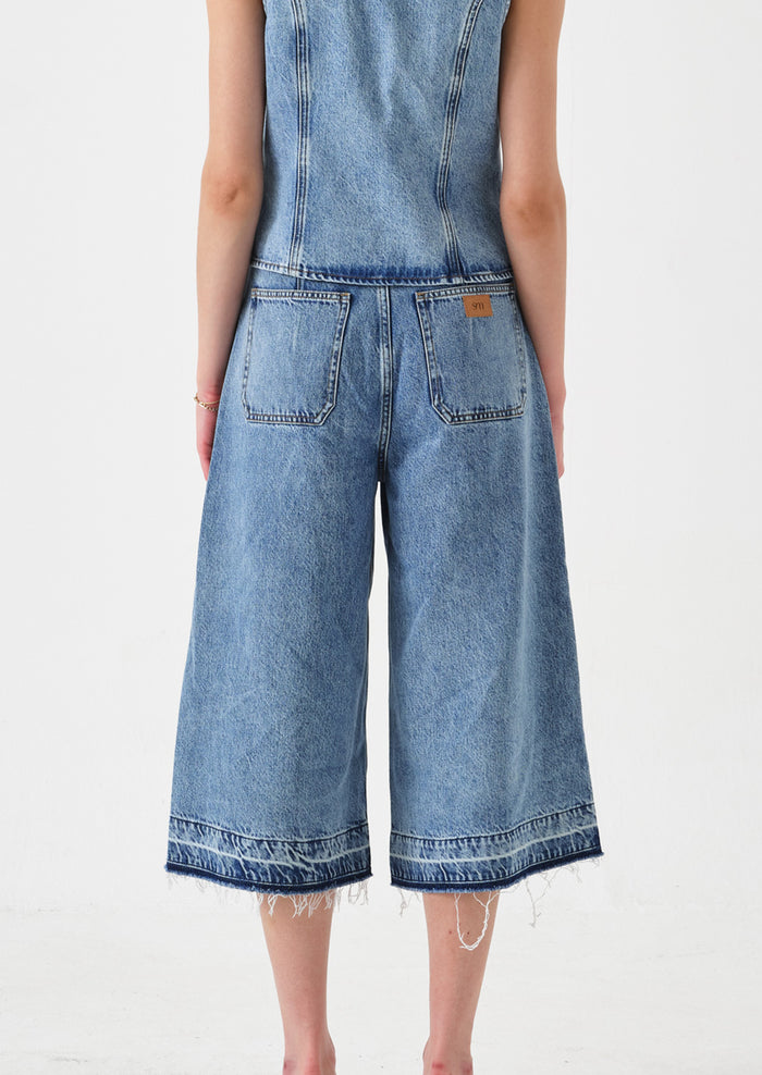 A person wearing a pair of denim culotte pants.