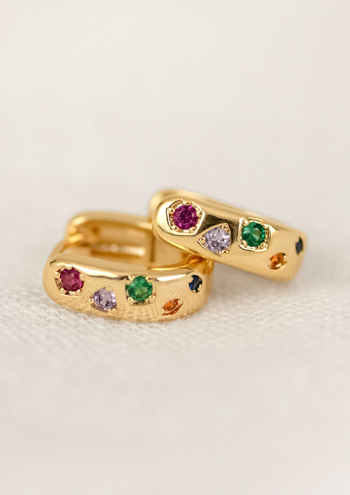 A pair of gold hoops adorned with colorful gems.