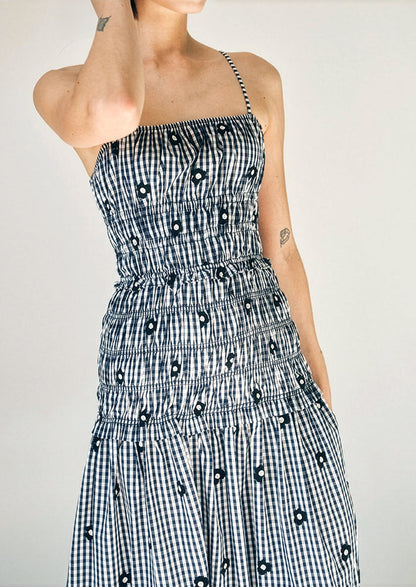 Person wearing a black and white checkered dress with a pattern of black shapes on a plain background